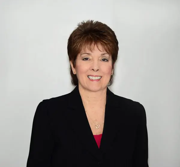 Professional portrait of a middle-aged woman in a black blazer.
