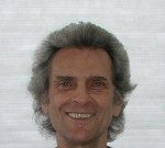 Dancing with Gravity Smiling man with gray hair against a light background.