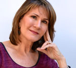 Into the Void: A Journey of Longing, Love and Eros Smiling middle-aged woman with hand resting on her face.