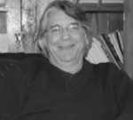 The Handbook of Body Psychotherapy and Somatic Psychology: A Day Long Celebration Smiling man wearing glasses and a dark sweater, seated indoors.