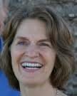 The Handbook of Body Psychotherapy and Somatic Psychology: A Day Long Celebration Smiling woman with brown hair and blue shirt outdoors.