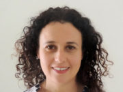 Thoughts about Addiction, Memory, Trauma and Somatic Experiencing® Smiling woman with curly hair in a patterned top.