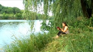 stock-footage-girl-reads-the-book-on-the-bank-of-river-1