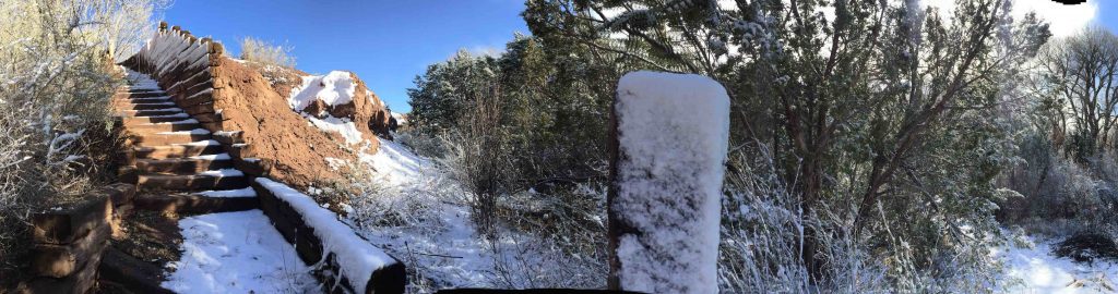 Snow-covered pillar and trees on a sunny day.