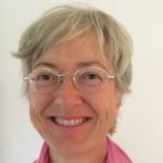 Smiling person with glasses and short hair.