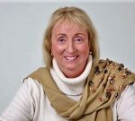 Attachment Theory Smiling woman with beige scarf and sweater.