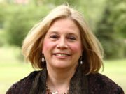 The Power of Attachment – Author Reflections Smiling woman outdoors with a light breeze.