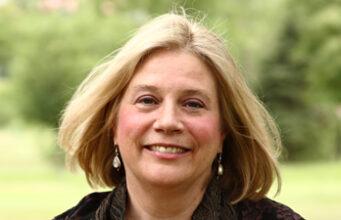 The Power of Attachment – Author Reflections Smiling woman outdoors with a light breeze.