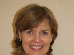 Embodied Awareness – Ferocious Family Love Smiling woman with short brown hair and a grey top.
