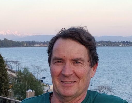 Drumming as Somatic Therapy Man smiling by a lakeside at sunset.